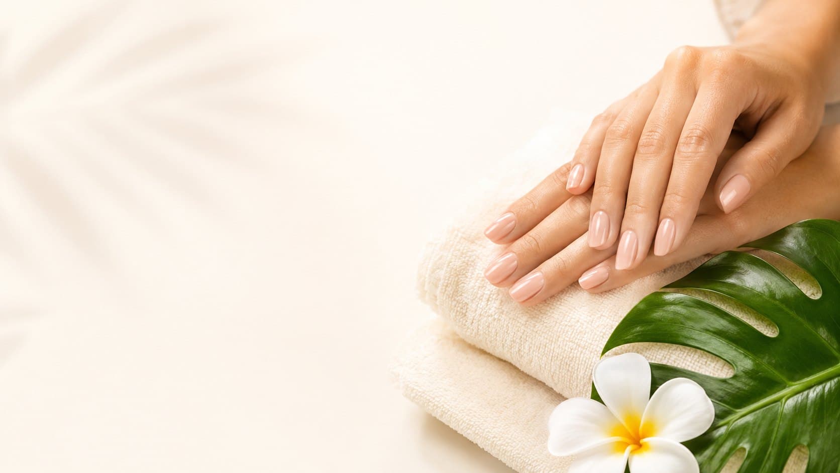 Elegant manicured hands with a monstera leaf and plumeria at Kailua Nail Care